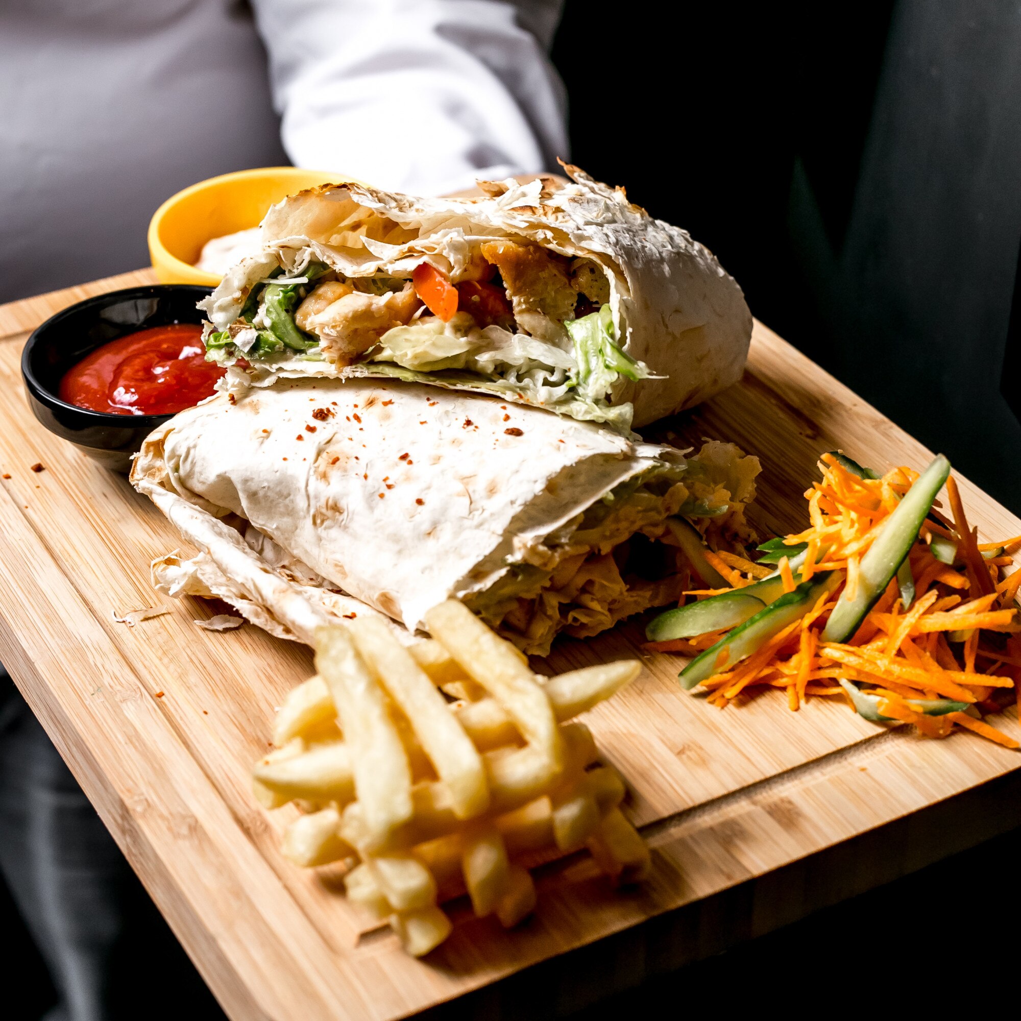 side view man holds tray with chicken doner pita bread with ketchup mayonnaise french fries vegetable salad board 141793 2869